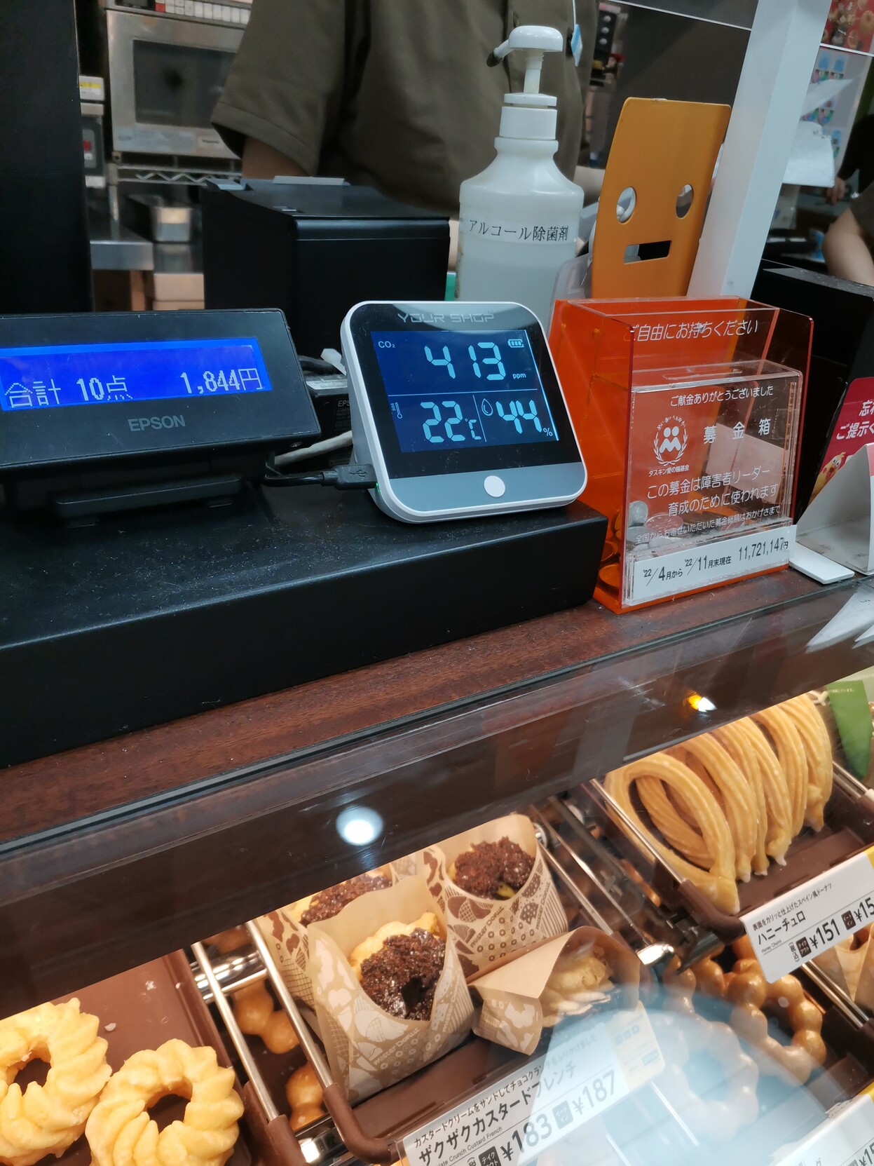 CO2 Monitor on top of the donut shop counter reads 413 ppm. 22 degrees Celsius and 44 percent humidity. 