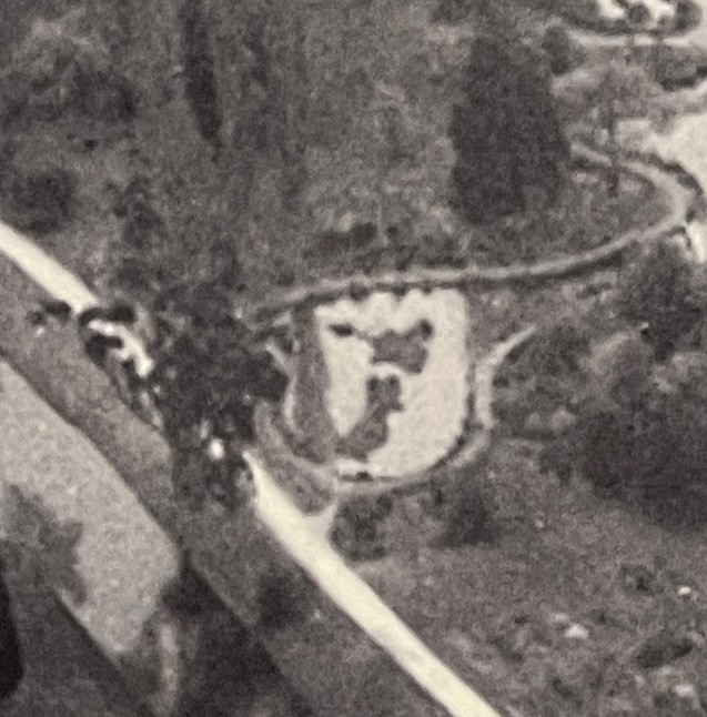 A cropped photo of part of an old black-and-white aerial photo of the Christchurch Botanic Garden from around 1935 showing a lake with two islands in it the shape of NZ's North Island and South Island.