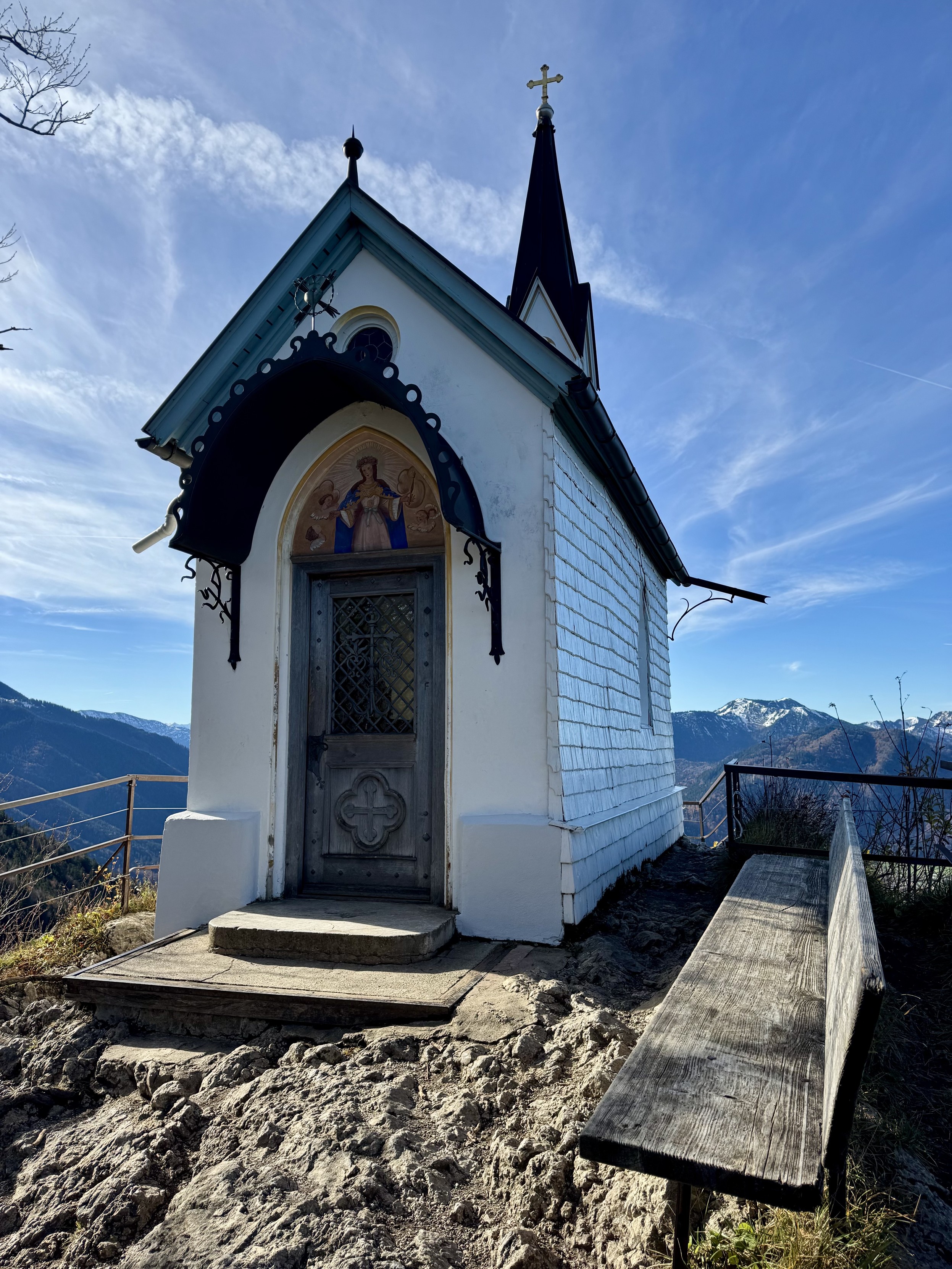 View of chapel entrance with exposed bedrock & bench in foreground