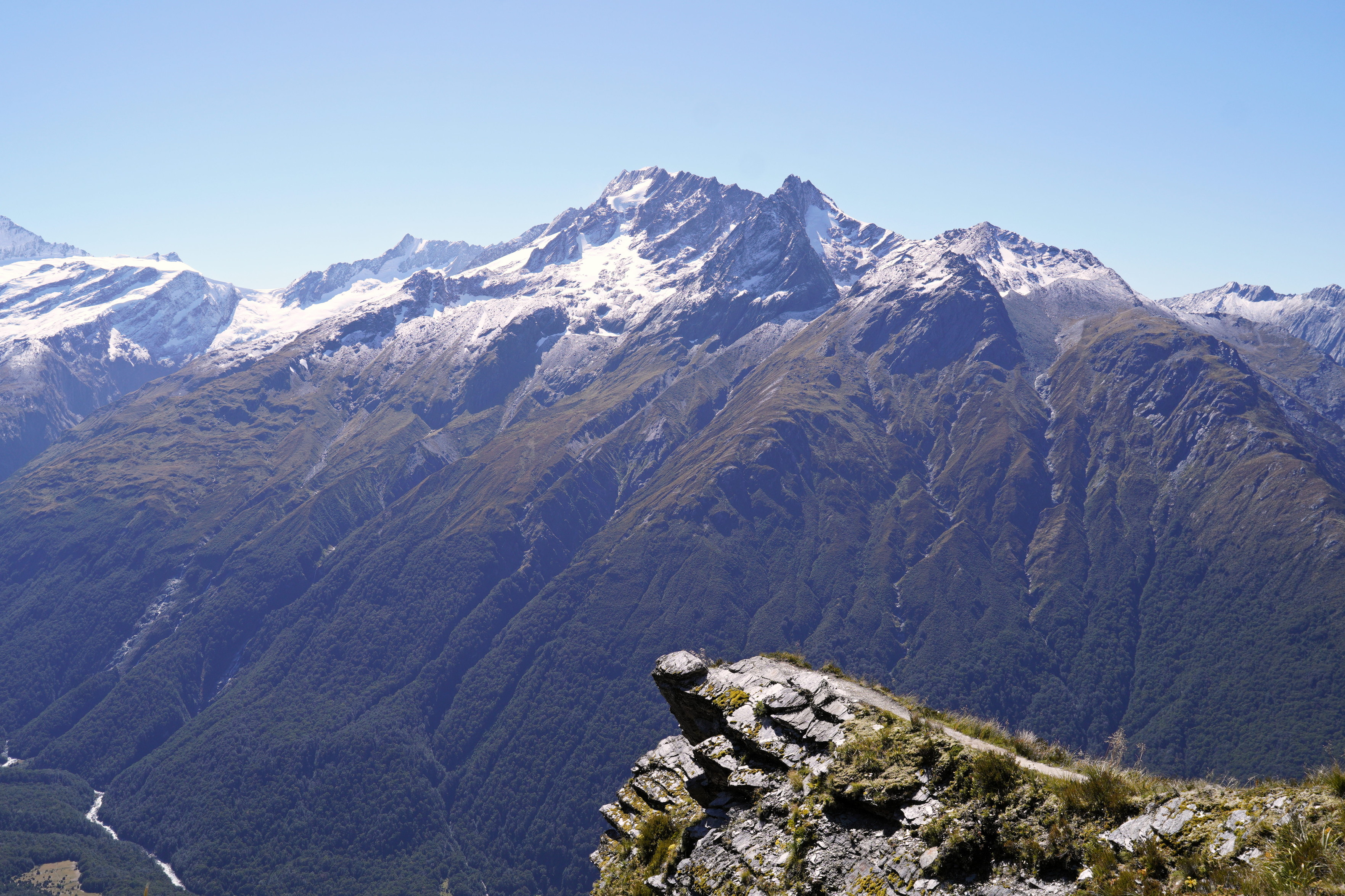 The famous Instagram spot on the climb up to the Cascade Saddle. There is a diving-board-like outcrop of rock, with snow-capped mountains in the background (though not Mt Aspiring).
