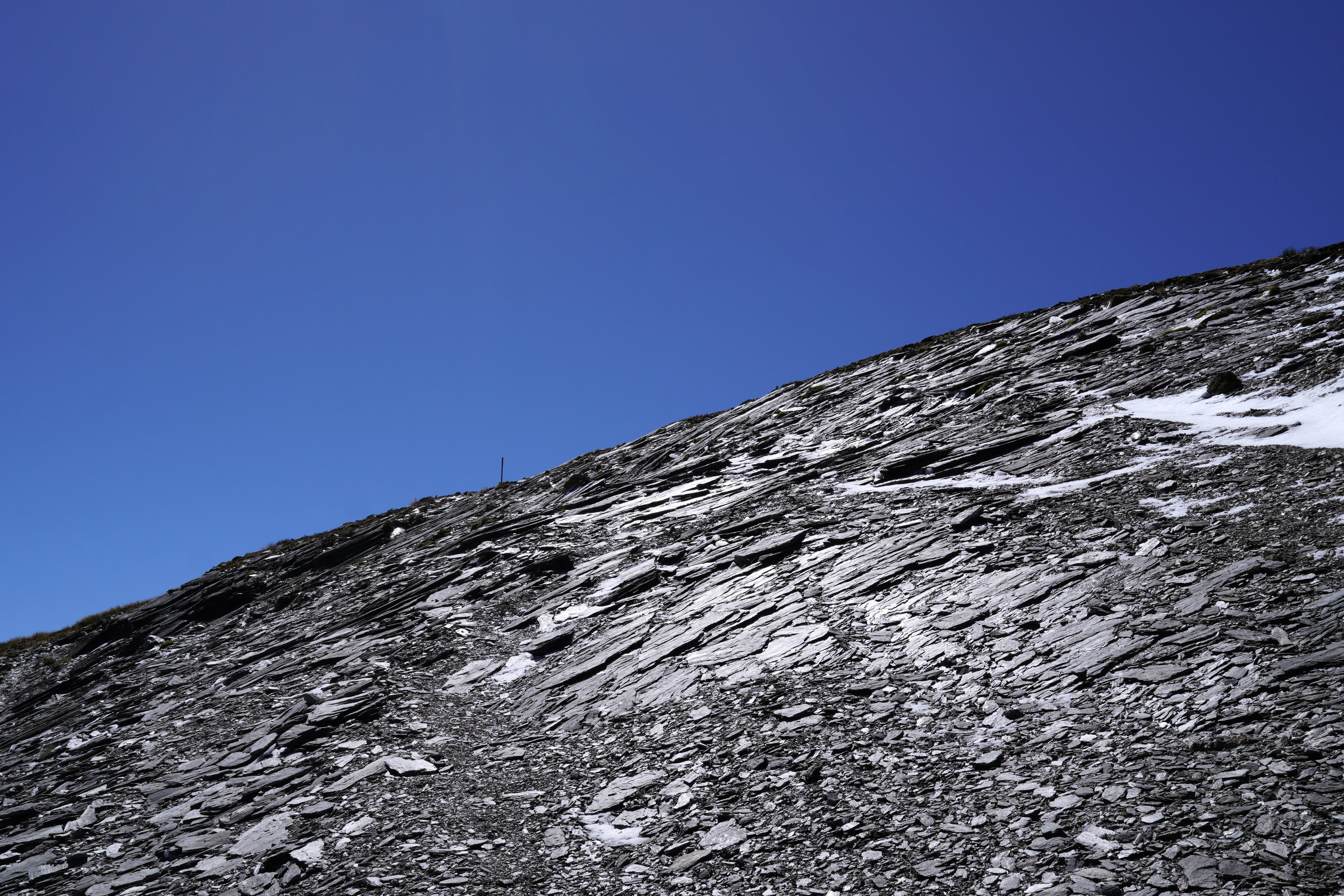 After reaching the high point, there is a bunch of shale to cross, which is easier than it looks. We climbed on a day with bluebird sky. There is a marker pole in the distance.