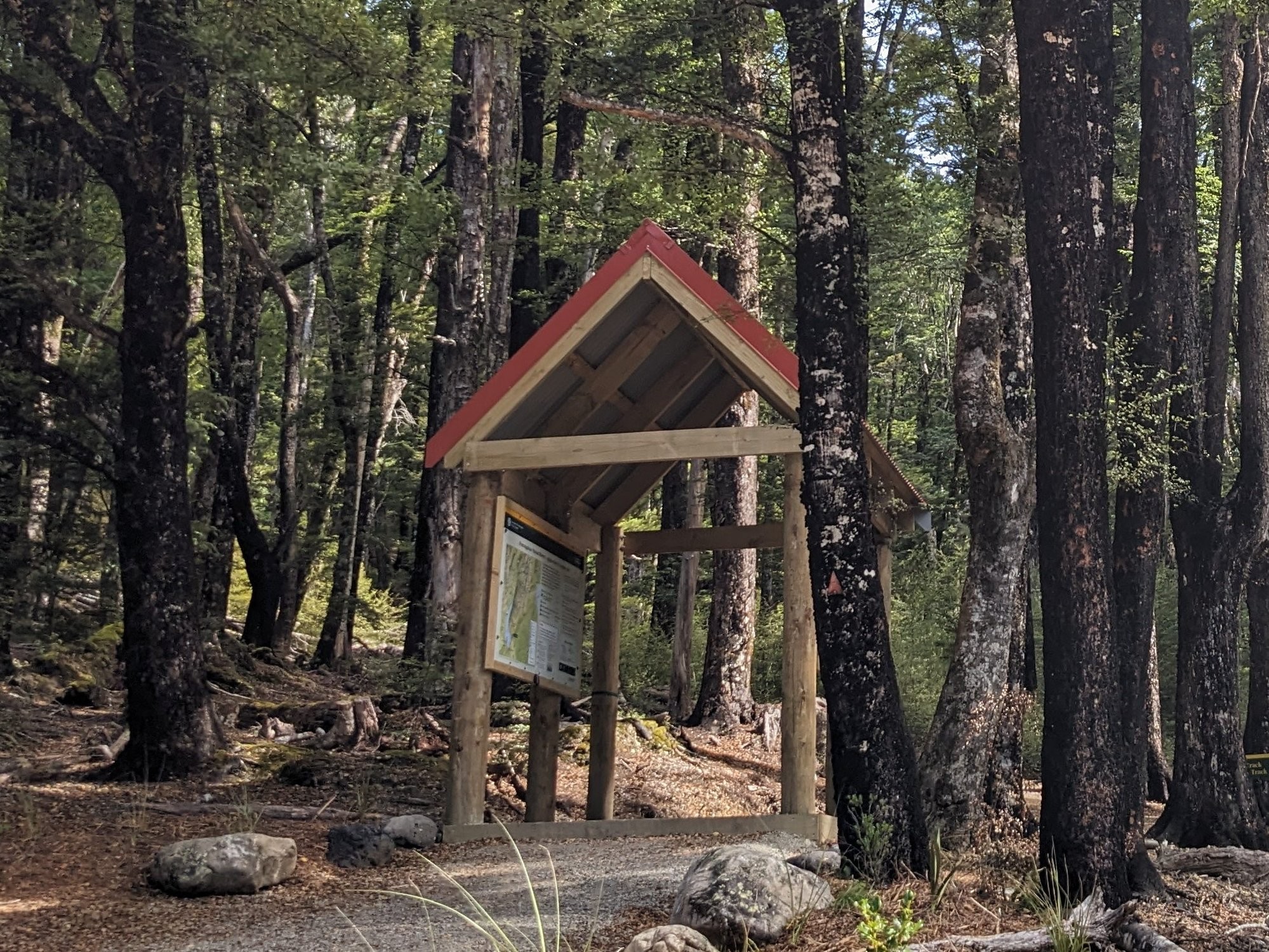 A gateway arch indicating the start of a track. Contains a poster board with information about the tracks. Leads to a track in the forest.