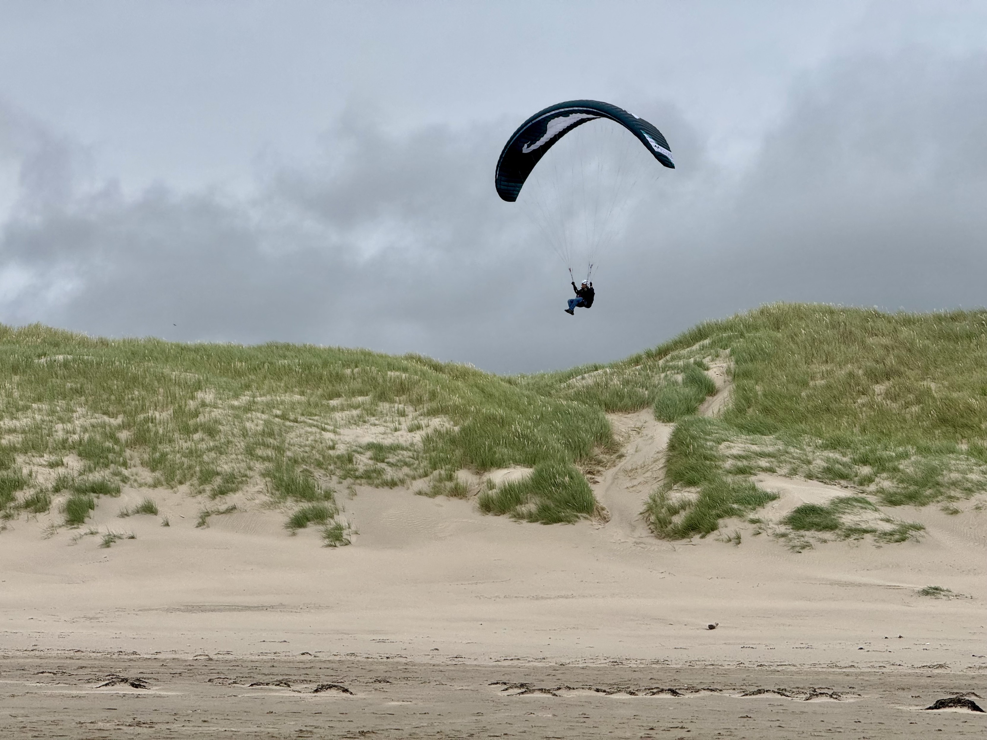 Paraglider ridge soaring along coastal sand dunes